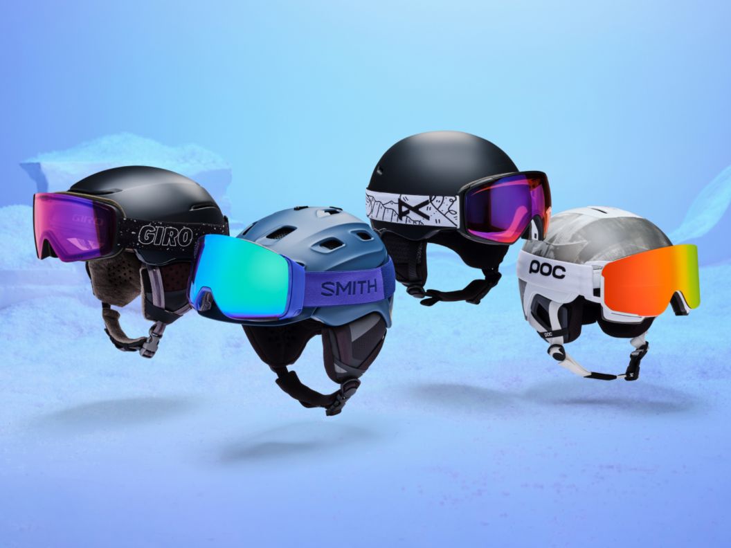 Four helmets with colorful goggles on them floating over a drab background.
